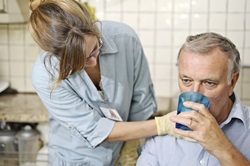 Nursing staff member helping patient to drink a glass of water