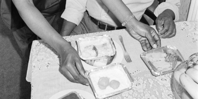 crop of a black and white photo of someone placing dinner on a table