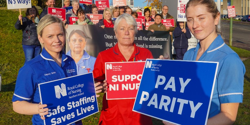Nursing staff in Northern Ireland hold placards reading 'Safe staffing saves lives' and 'pay parity'