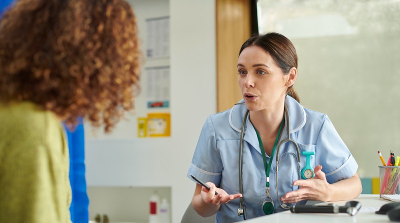 Female nurse speaking to a blurred image of a patient