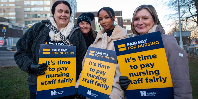 Nursing staff holding fair pay for nursing signs