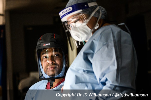 Two nurses in PPE looking at each other. Photo by Dr. JD Williamson.